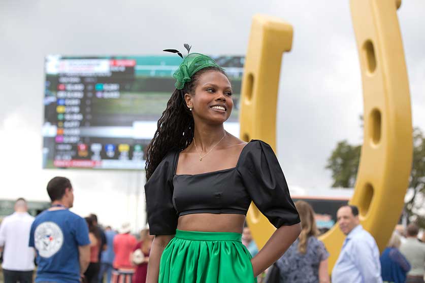 A lady in green posing at the Queen's Plate at Woodbine Racetrack