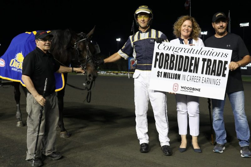 Bob McClure celebrates with Forbidden Trade as the trotter reaches the $1 million milestone. (New Image Media) 