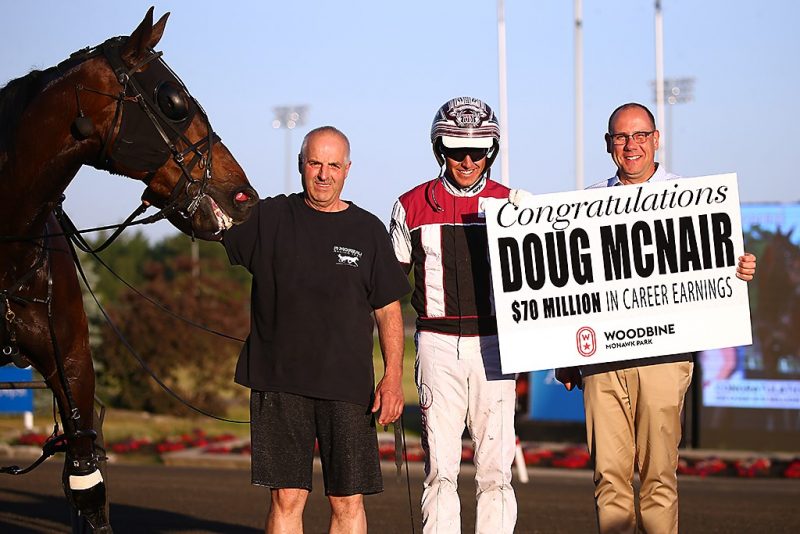 Doug McNair receives a sign recognizing $70 million from Bill McLinchey, Director of Standardbred Racing. (New Image Media)