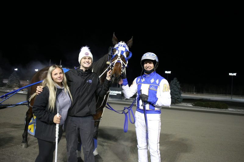 Travis Forbes and Victoria MacInnis with Malvolio and driver James MacDonald in the Woodbine Mohawk Park winner's circle on December 1, 2022 (New Image Media)