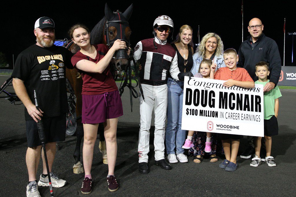 Doug McNair is joined by family and friends following his milestone moment. Bill McLinchey, Vice-President of Standardbred Racing, made the sign presentation. (New Image Media)