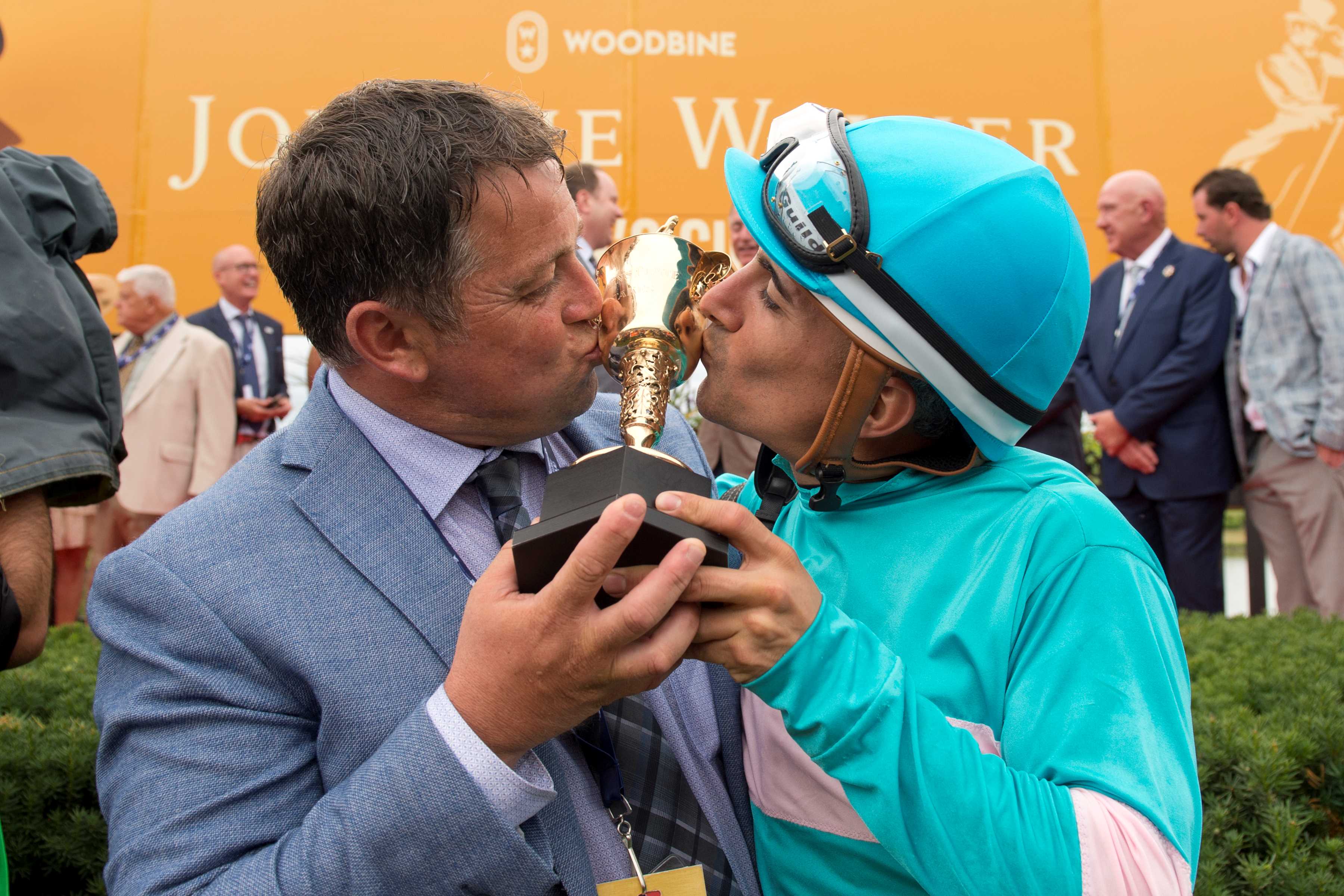 Kevin Attard and Rafael Hernandez kiss the Queen's Plate trophy after Moira's win in 2022 (Michael Burns Photo)