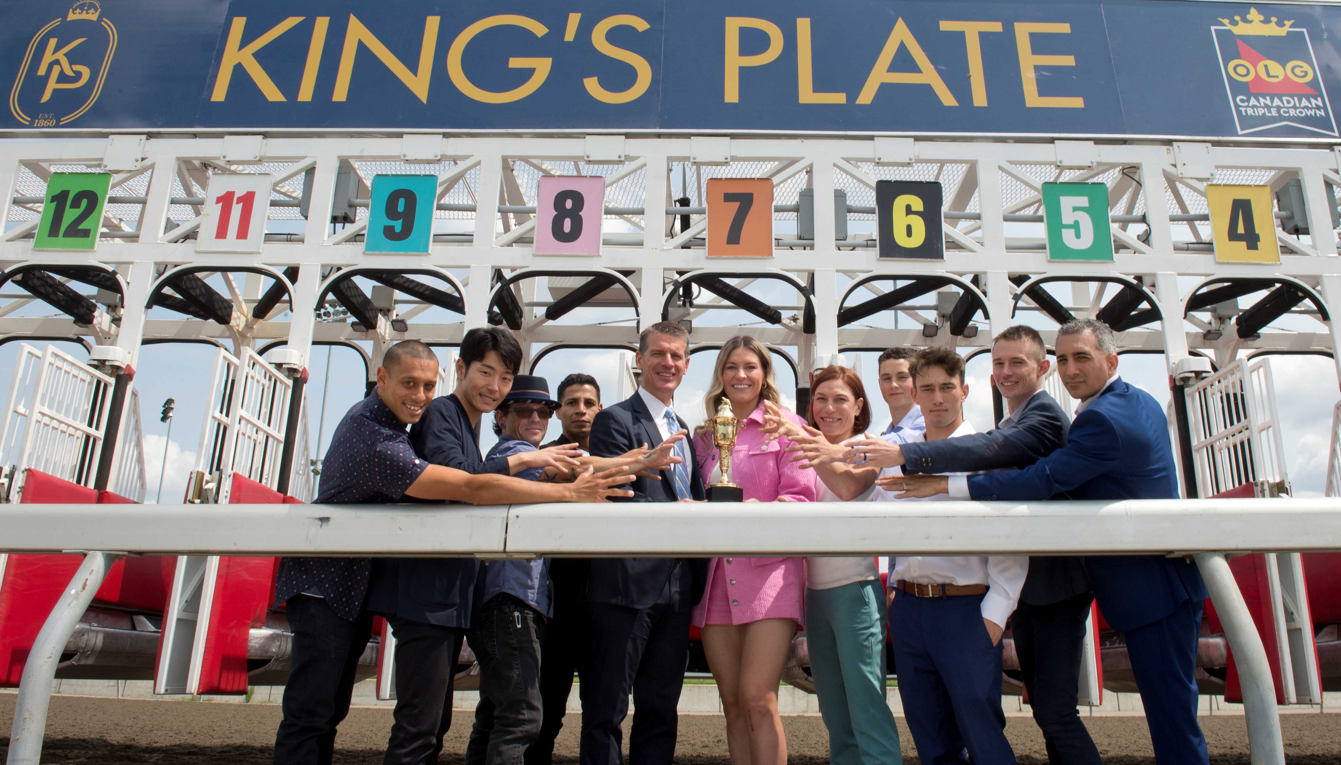 Jockeys to race in the 2024 King's Plate reach for the trophy held by Woodbine CEO Michael Copeland and special guest Natalie Spooner (Michael Burns Photo)